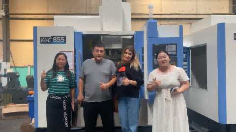 Representatives from both the Chinese and foreign sides stand shoulder to shoulder for a group photo in front of a large CNC machine tool, holding the signed cooperation agreement, with the machine's control screen displaying an operational interface in the background.